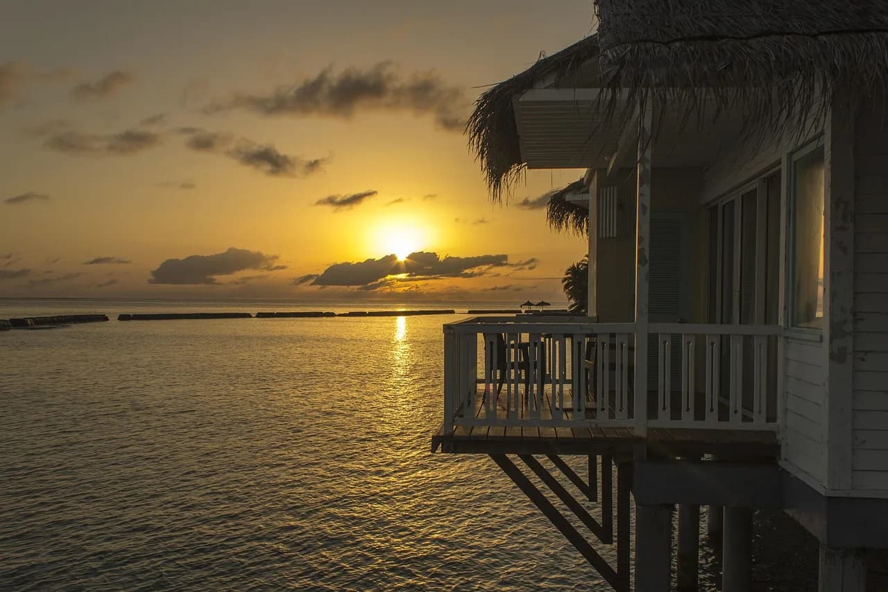Vilë mbi ujë në perëndim të diellit, Maldive – bungalov prej druri mbi lagunë tirkiz